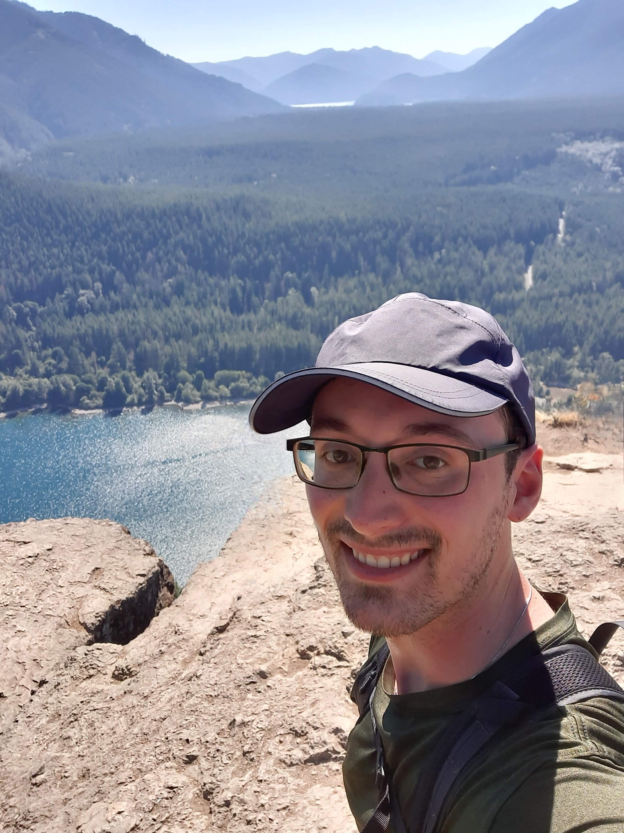 Photo of Connor standing on top of cliff in a baseball cap